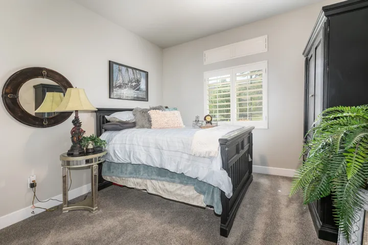 Carpeted room featuring a window with plantation shutters, white baseboards, and light neutral wall paint