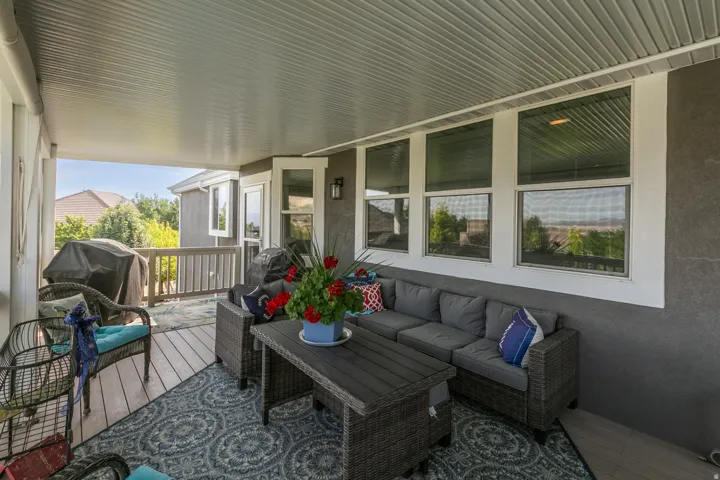 Covered deck featuring wood-finish flooring, a full-length white railing, and multiple windows