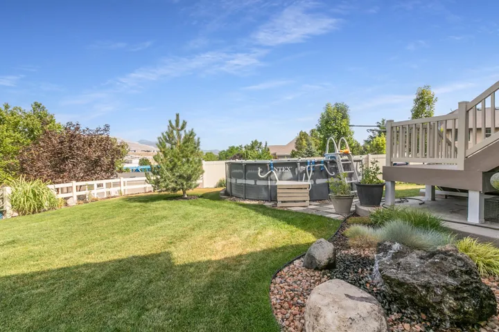 Expansive backyard featuring a large above-ground pool, a private elevated deck with stairs, and a manicured lawn