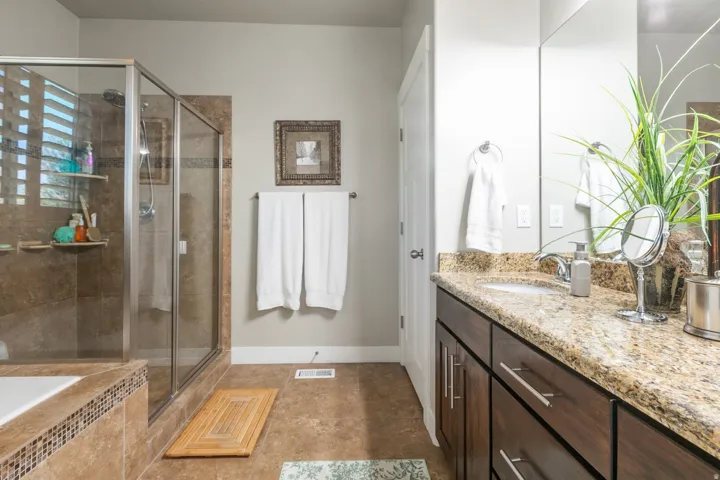 Bathroom featuring a dark wood-finish vanity with a light granite countertop and a single undermount sink