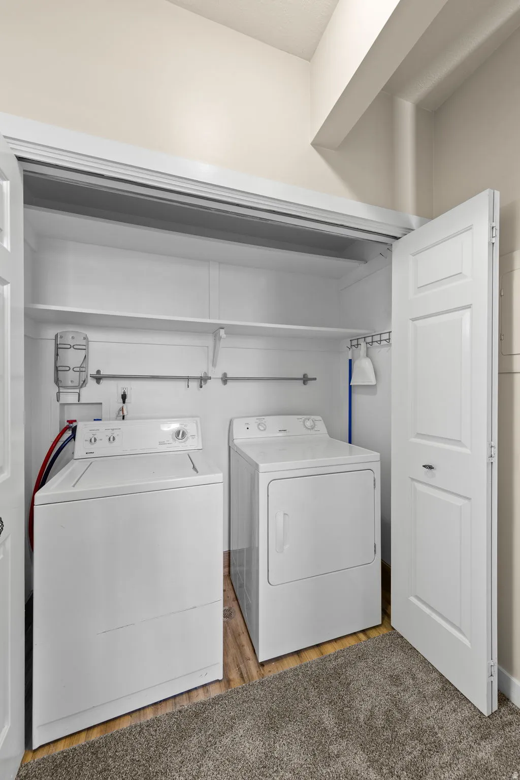 Dedicated laundry closet featuring a built-in shelf, hanging rod, and wood-finish flooring
