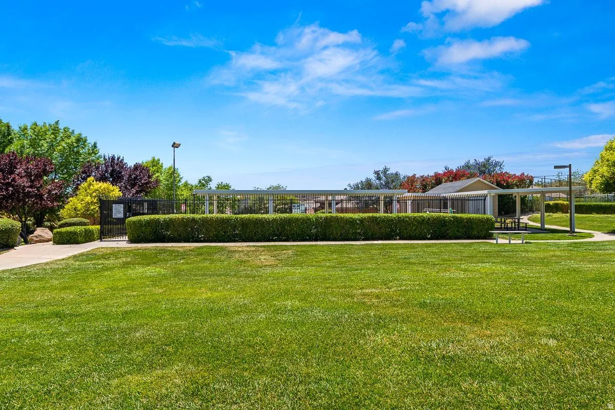 Expansive green lawn area featuring manicured hedges, mature landscaping, and a paved pathway