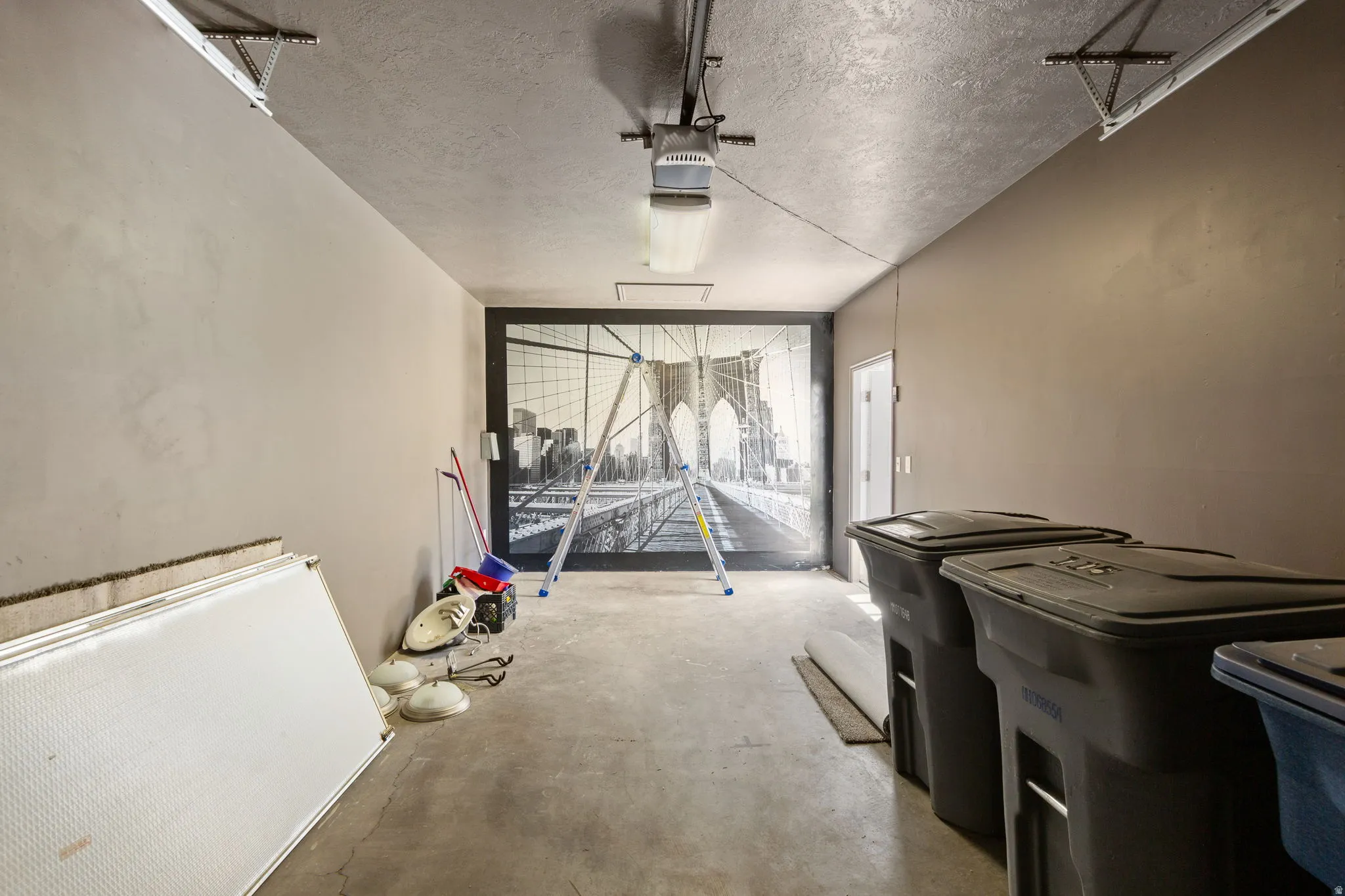 Spacious garage interior featuring concrete flooring, painted walls, and a prominent graphic wall covering