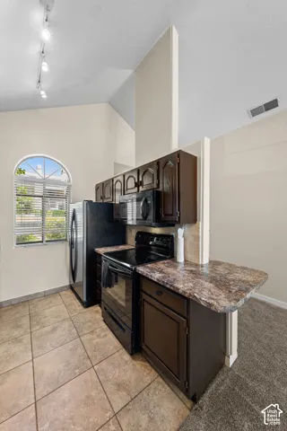 Kitchen featuring dark wood-finish cabinetry, black appliances, and a granite-finish countertop