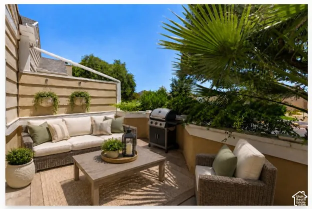 Outdoor patio space featuring a built-in privacy wall, a hard surface floor, and mature landscaping