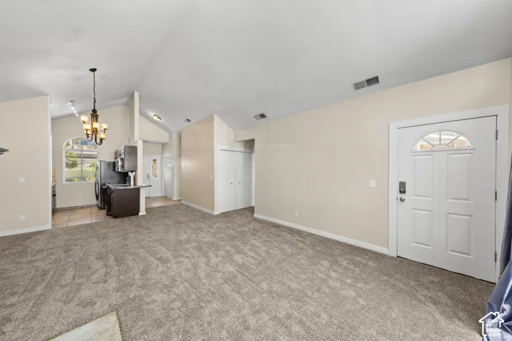 Spacious living area featuring vaulted ceilings and neutral carpeting