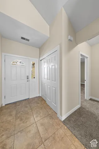 Foyer entry featuring ceramic tile flooring, a double front door with decorative glass inserts, and a bifold door closet