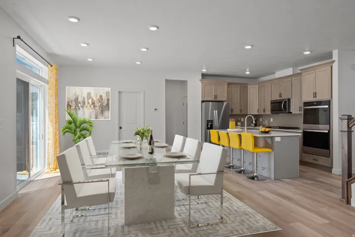 Open-concept living space featuring wood-finish flooring, recessed lighting, a sliding glass door, and a kitchen with stainless steel appliances, light-toned cabinetry, and a central island