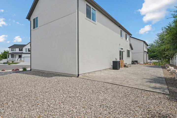 Spacious paver patio with a gravel border, featuring a stucco exterior and multiple windows