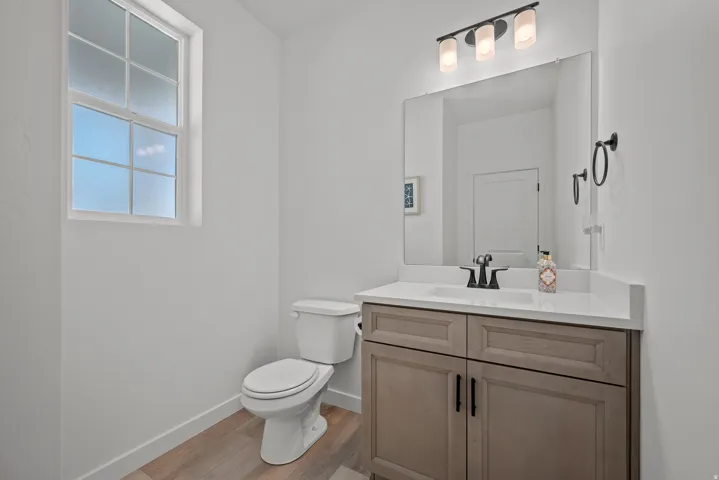 Vanity featuring a light wood-finish cabinet, white countertop, and matte black faucet