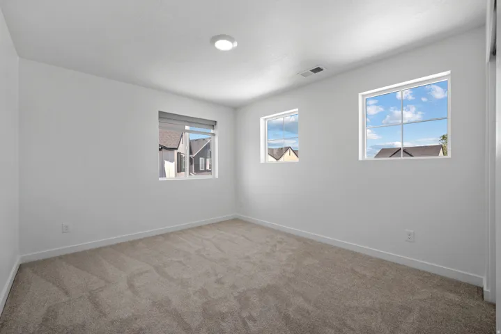 Interior room featuring light gray carpet, white painted walls, white trim, and three windows
