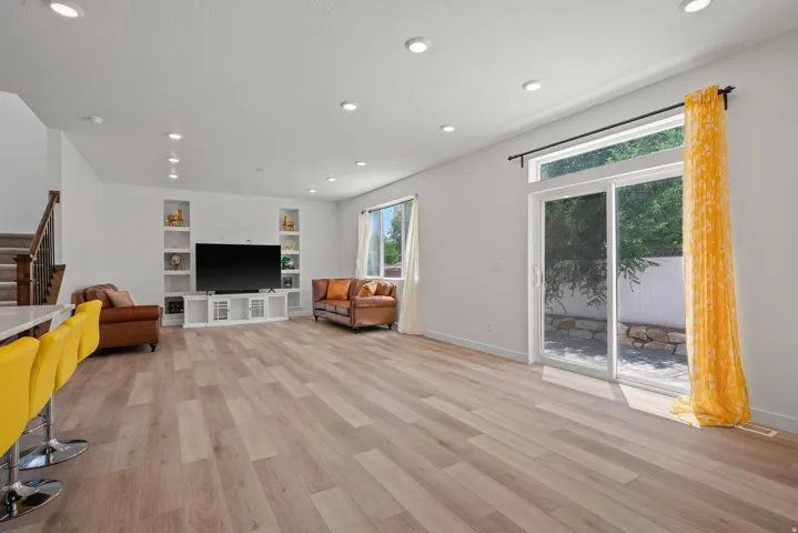 Spacious living area featuring light wood-finish flooring and recessed lighting