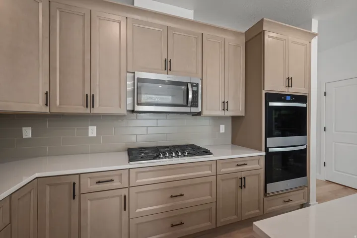 Kitchen featuring light wood-finish cabinetry, stainless steel appliances, a gas cooktop, light-toned countertops, and a subway tile backsplash
