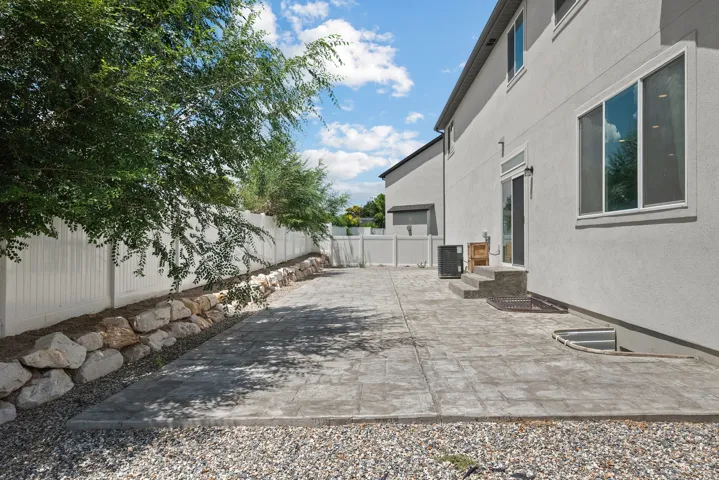 Private backyard featuring a stamped concrete patio, rock retaining wall, and mature landscaping