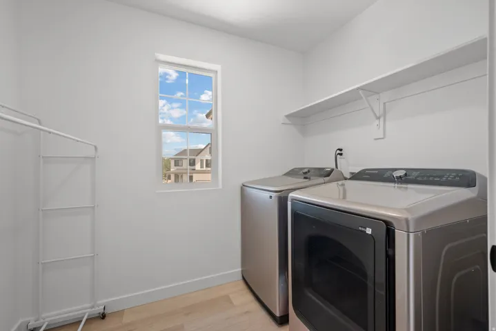 Laundry area featuring light wood-finish flooring and a window providing natural illumination