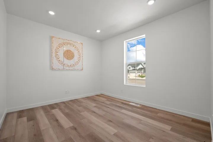 Room featuring wood-finish flooring, recessed lighting, and a single window with white trim