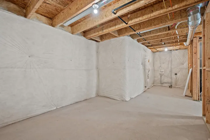 Unfinished basement featuring exposed wood joists, structural framing, and concrete flooring
