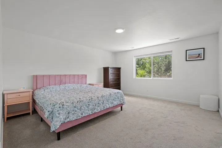 Spacious room featuring neutral carpeting, recessed ceiling lighting, and a large window with exterior greenery