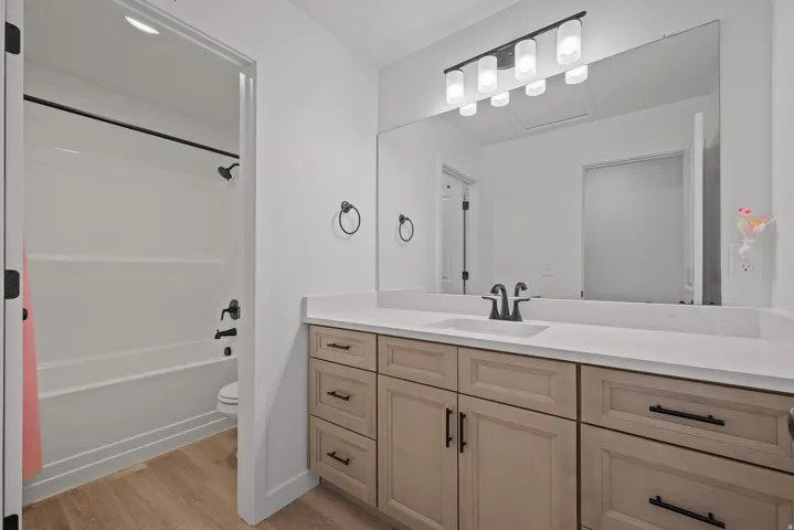 Bathroom featuring a spacious vanity with dual-tone cabinetry, a single basin sink, and a large mirror