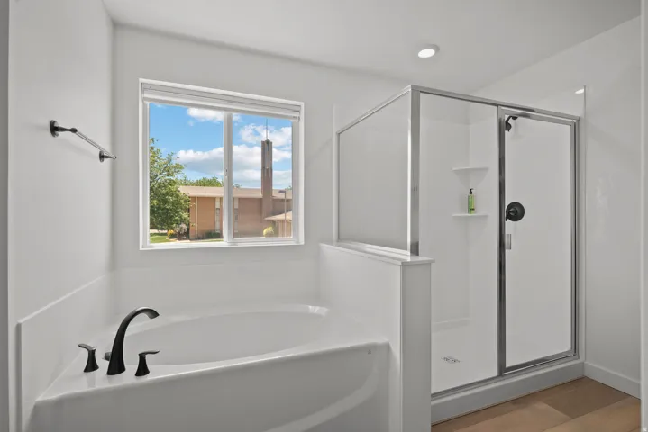 Soaking tub with black fixtures, framed by a window with white trim