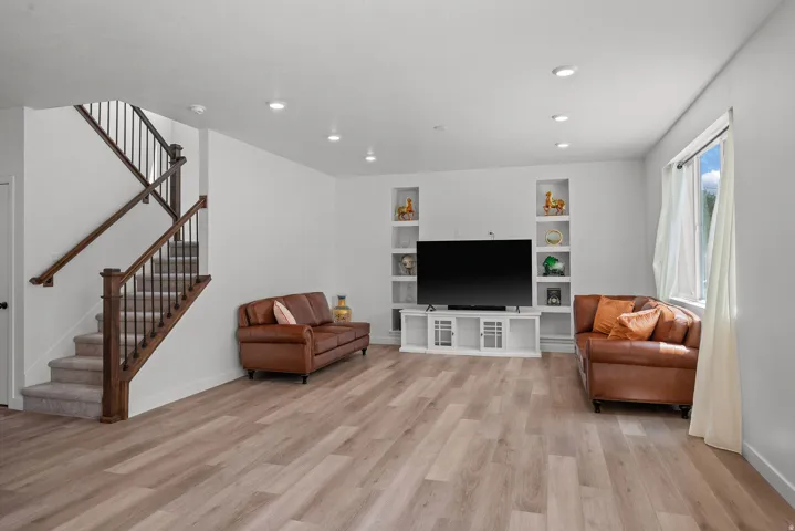 Spacious living area featuring wood-finish flooring, recessed lighting, and built-in display niches