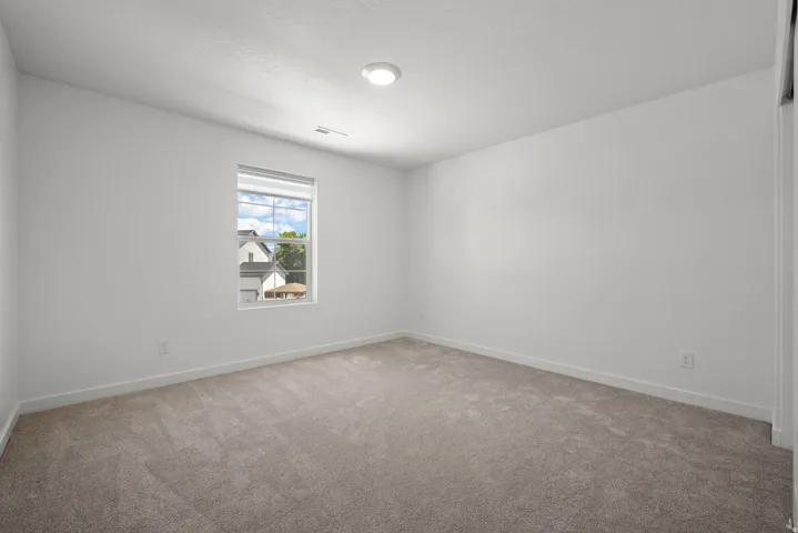Room featuring light gray carpeting, neutral wall color, and a window with blinds