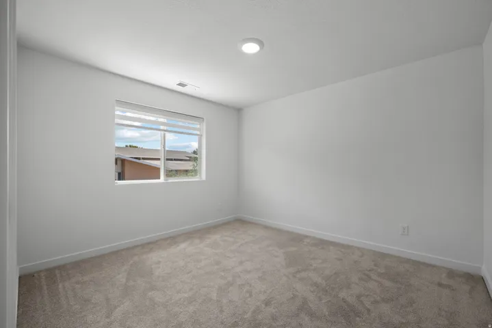 Room featuring neutral-toned carpeting, a single window with blinds, and recessed ceiling lighting