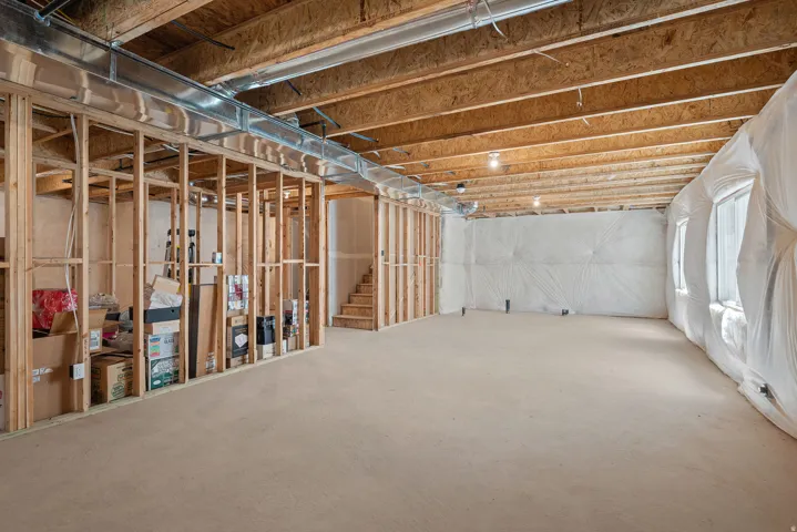 Lower level featuring framed partition walls, exposed ceiling joists, and a concrete floor