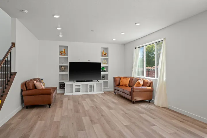 Spacious living area featuring contemporary built-in shelving, recessed lighting, and wood-finish flooring