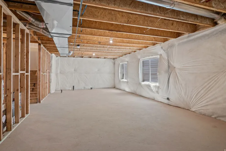 Unfinished basement with exposed wood framing, concrete flooring, and insulated exterior walls