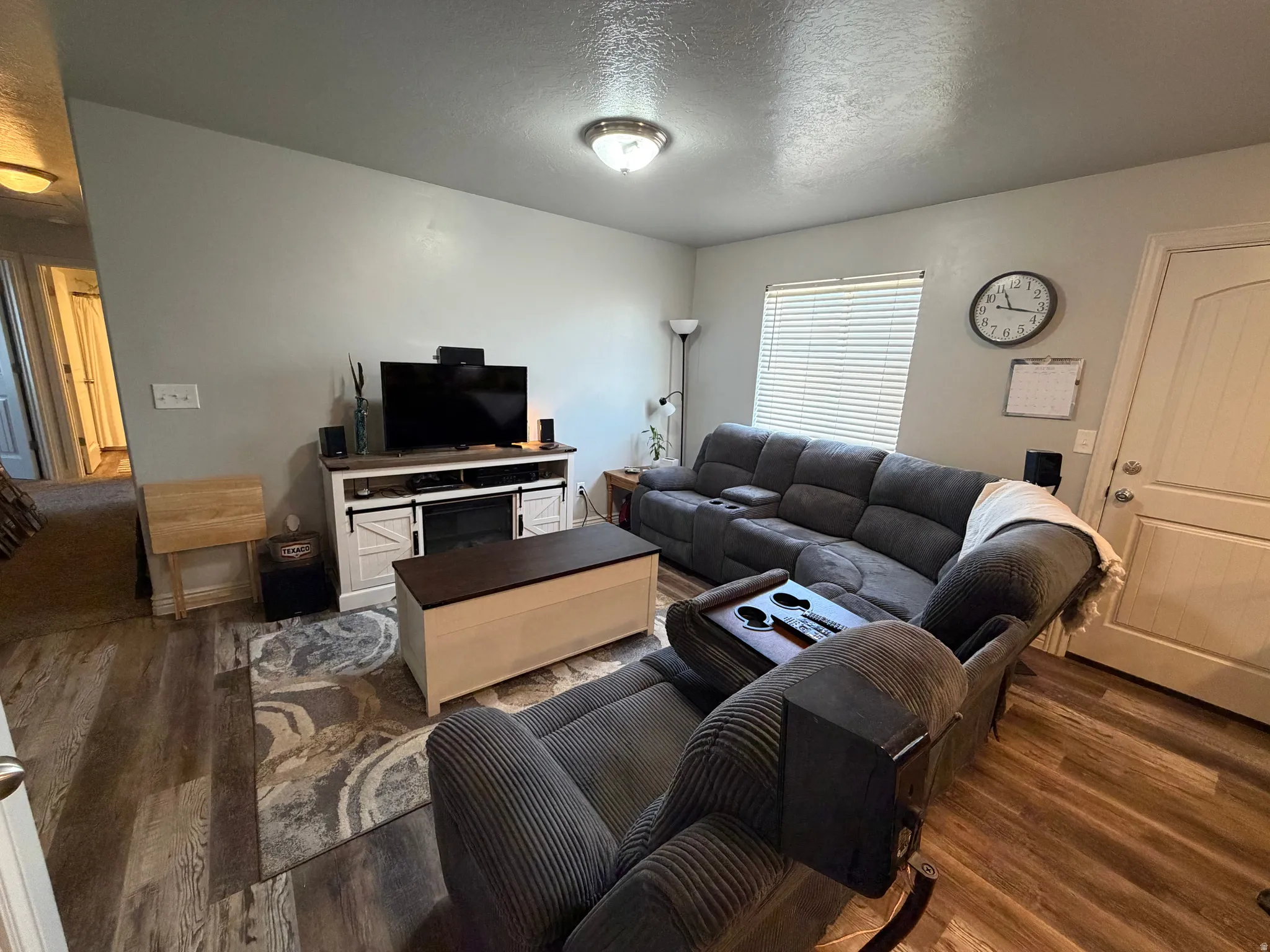 Living area featuring wood-finish flooring, light gray walls, a built-in media console with barn-door style cabinet fronts, and a ceiling-mounted light fixture