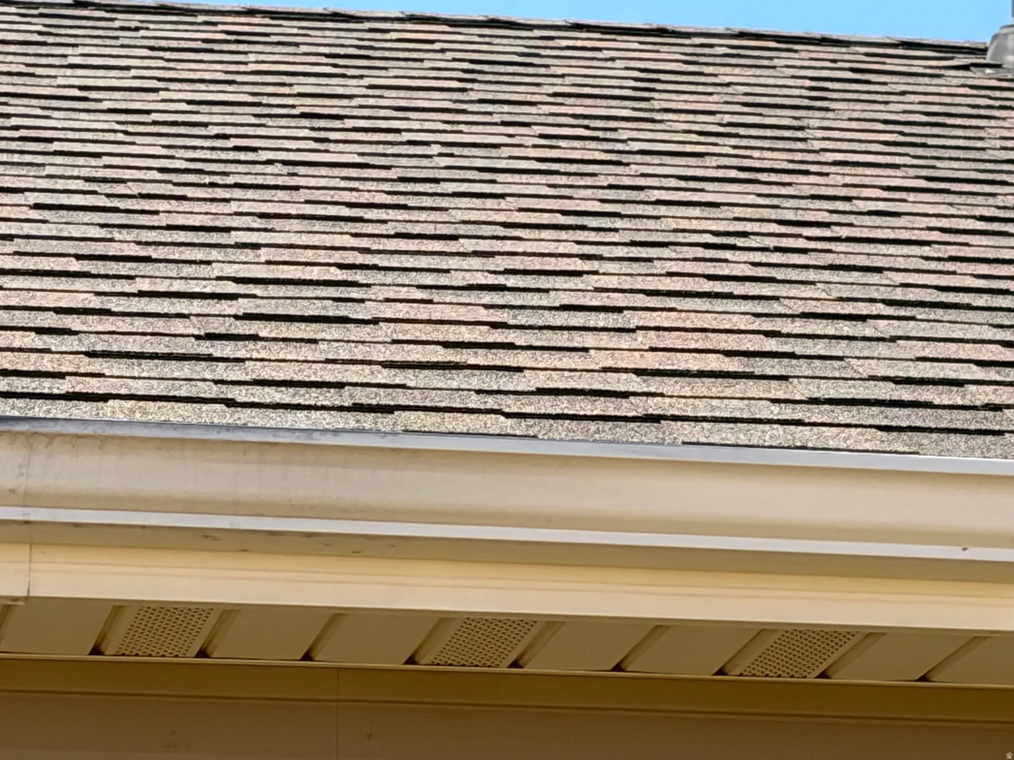 Asphalt shingle roof with light-colored gutters and perforated soffit panels