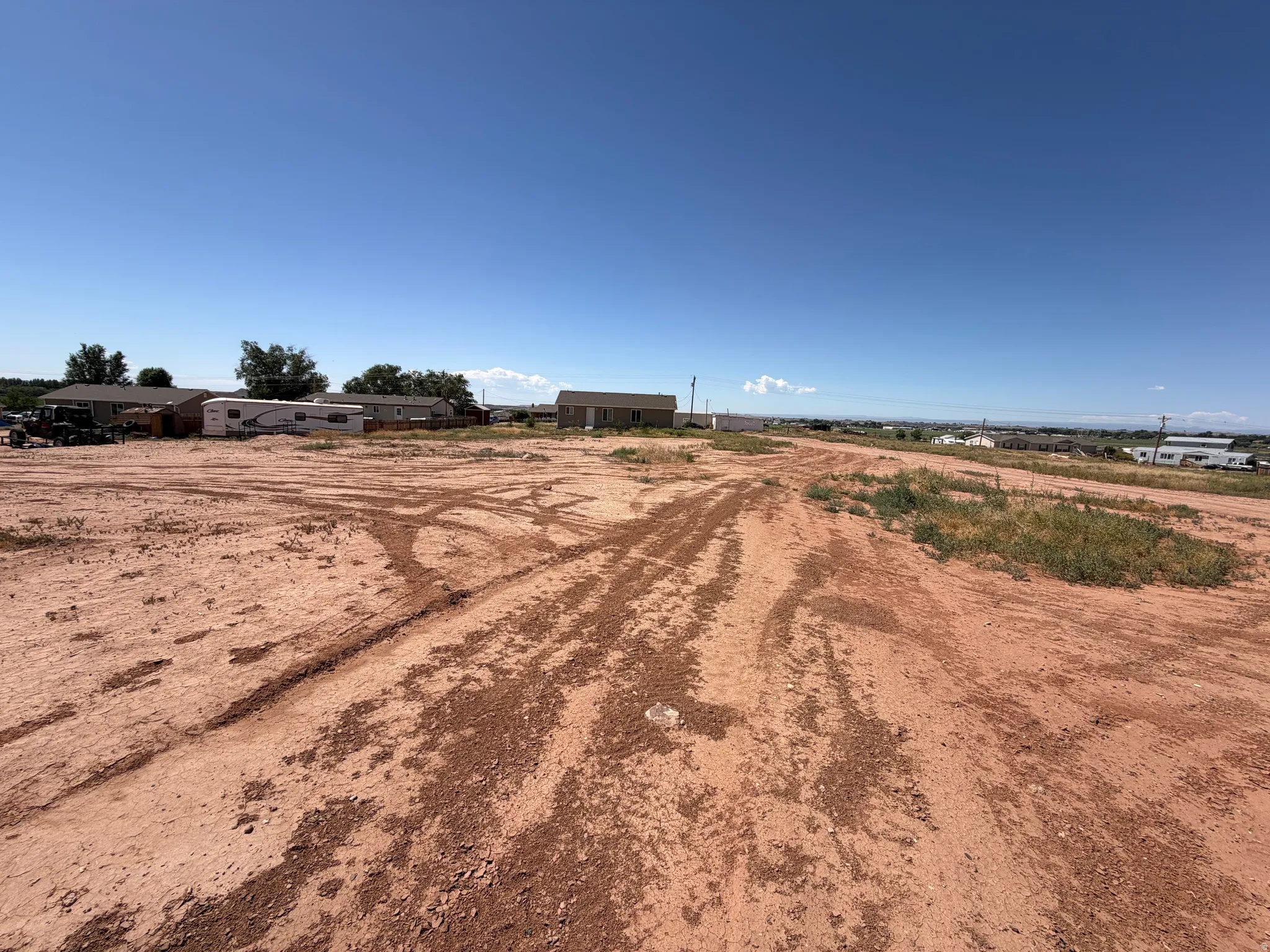 Expansive undeveloped lot featuring red earth and scattered natural vegetation