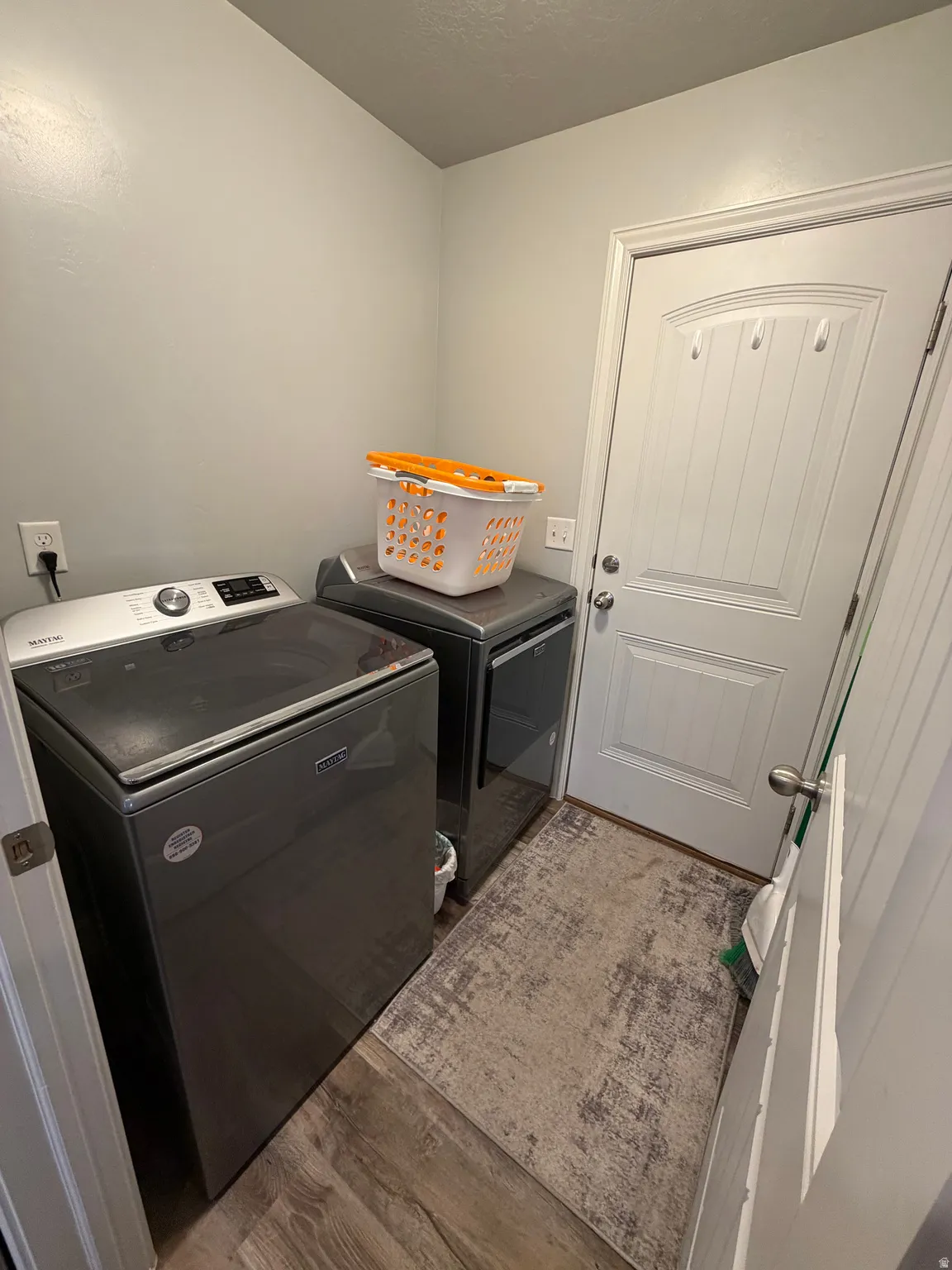 Dedicated laundry area featuring wood-finish flooring, light grey walls, and a white paneled door