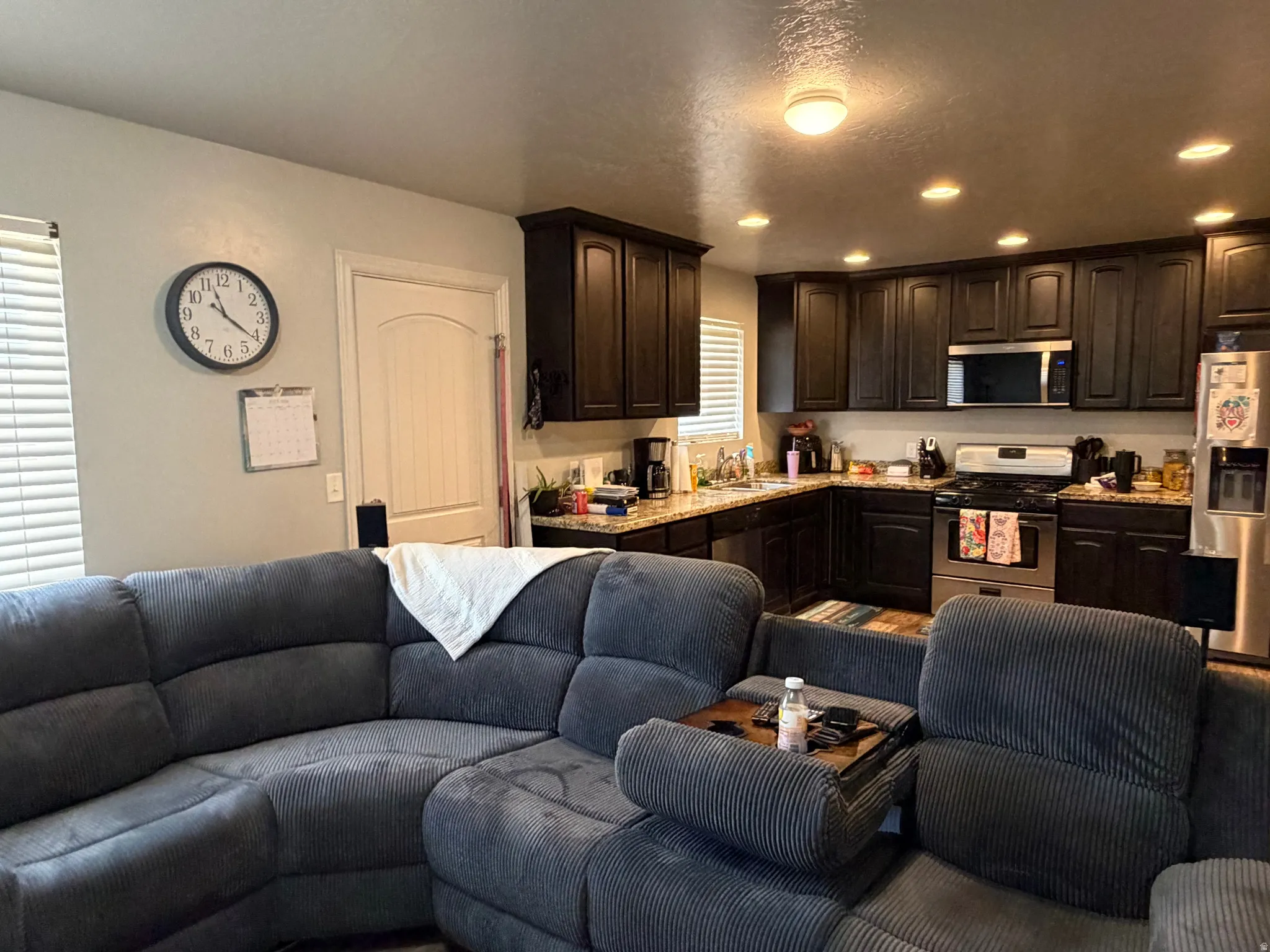 Kitchen featuring dark wood cabinetry, stainless steel appliances, granite-look countertops, and recessed lighting