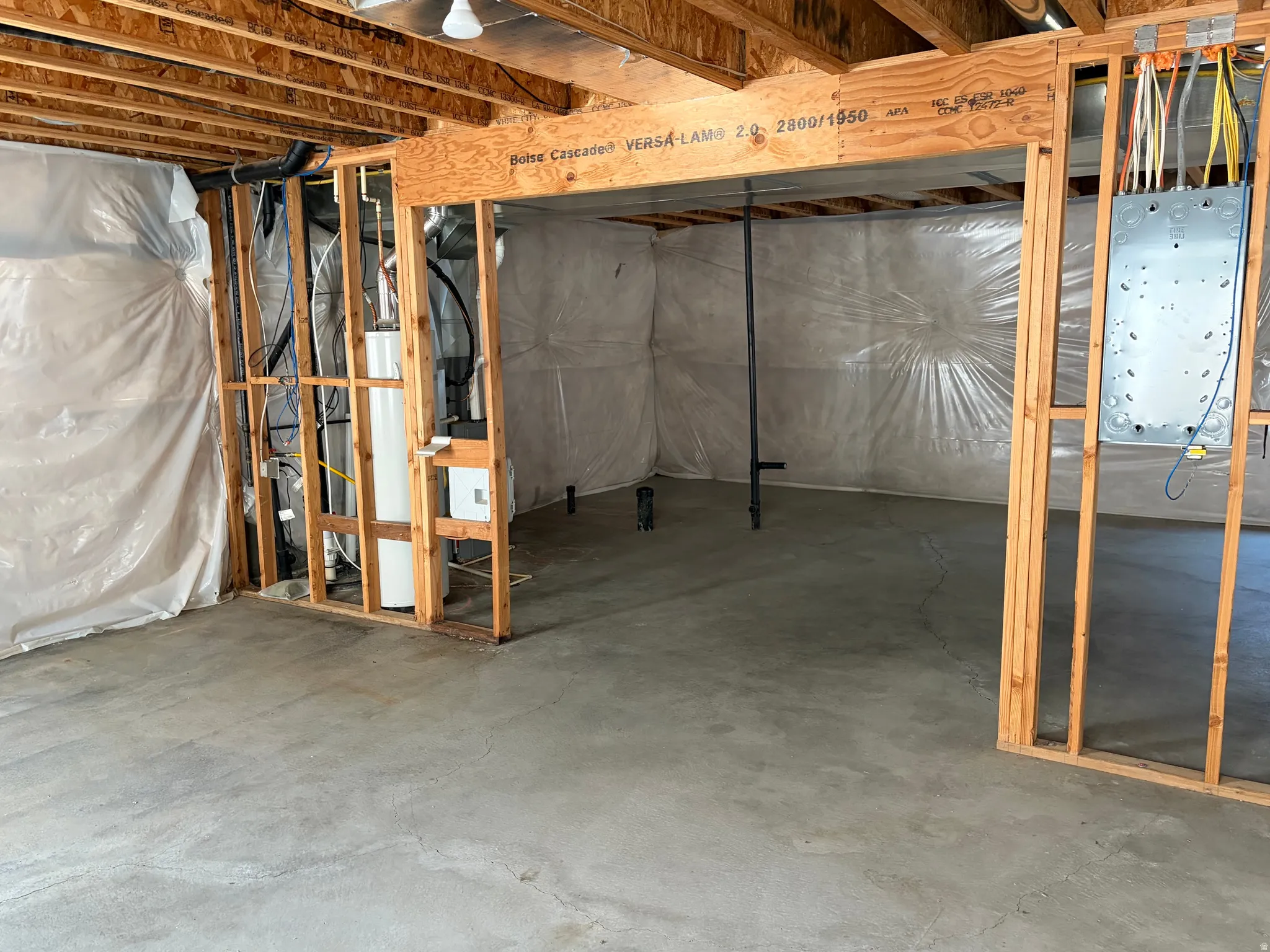 Unfinished lower level featuring exposed wood framing, concrete flooring, and utilities including a water heater and electrical panel