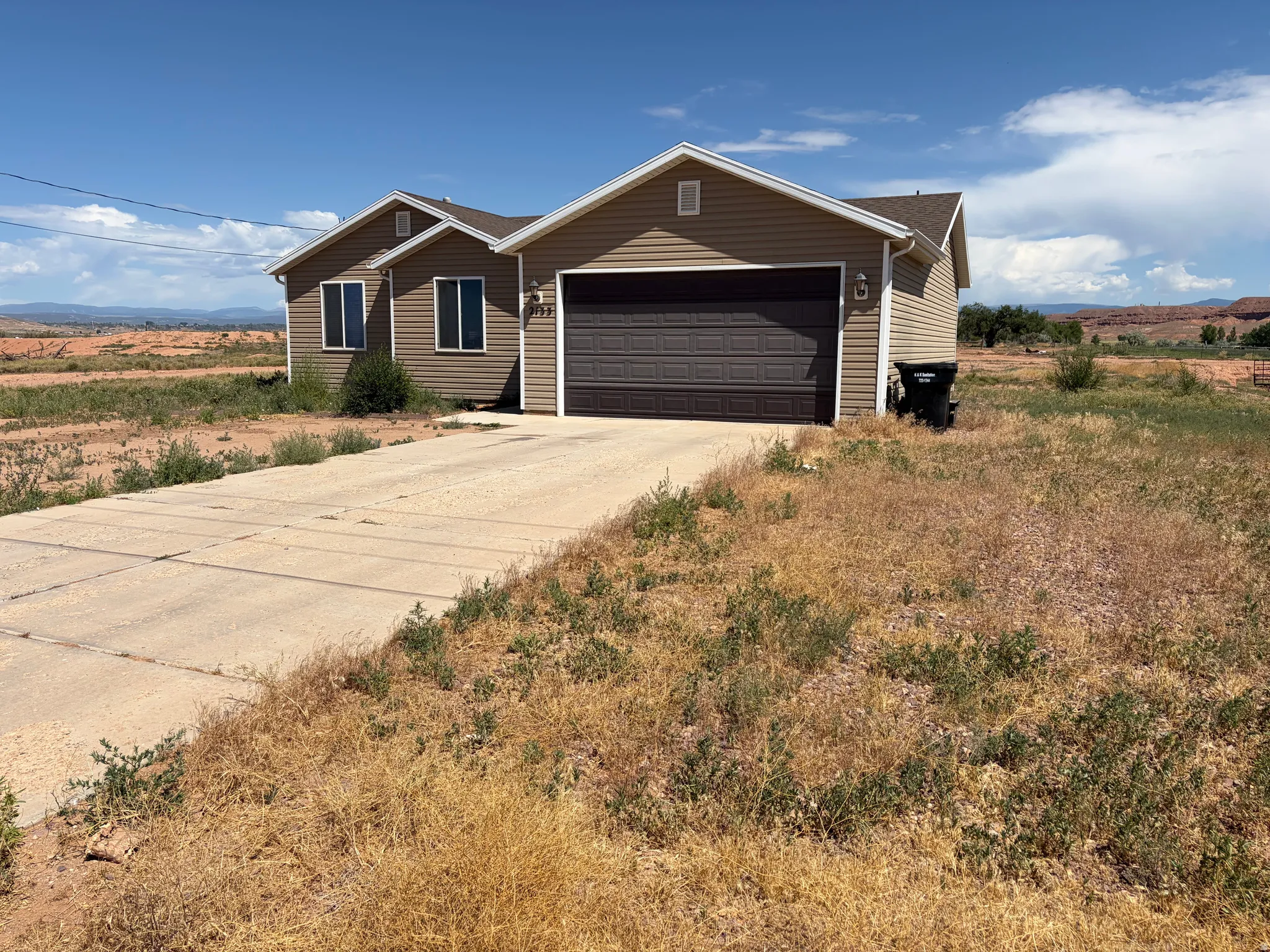 Single-story residence featuring light brown siding and a brown garage door