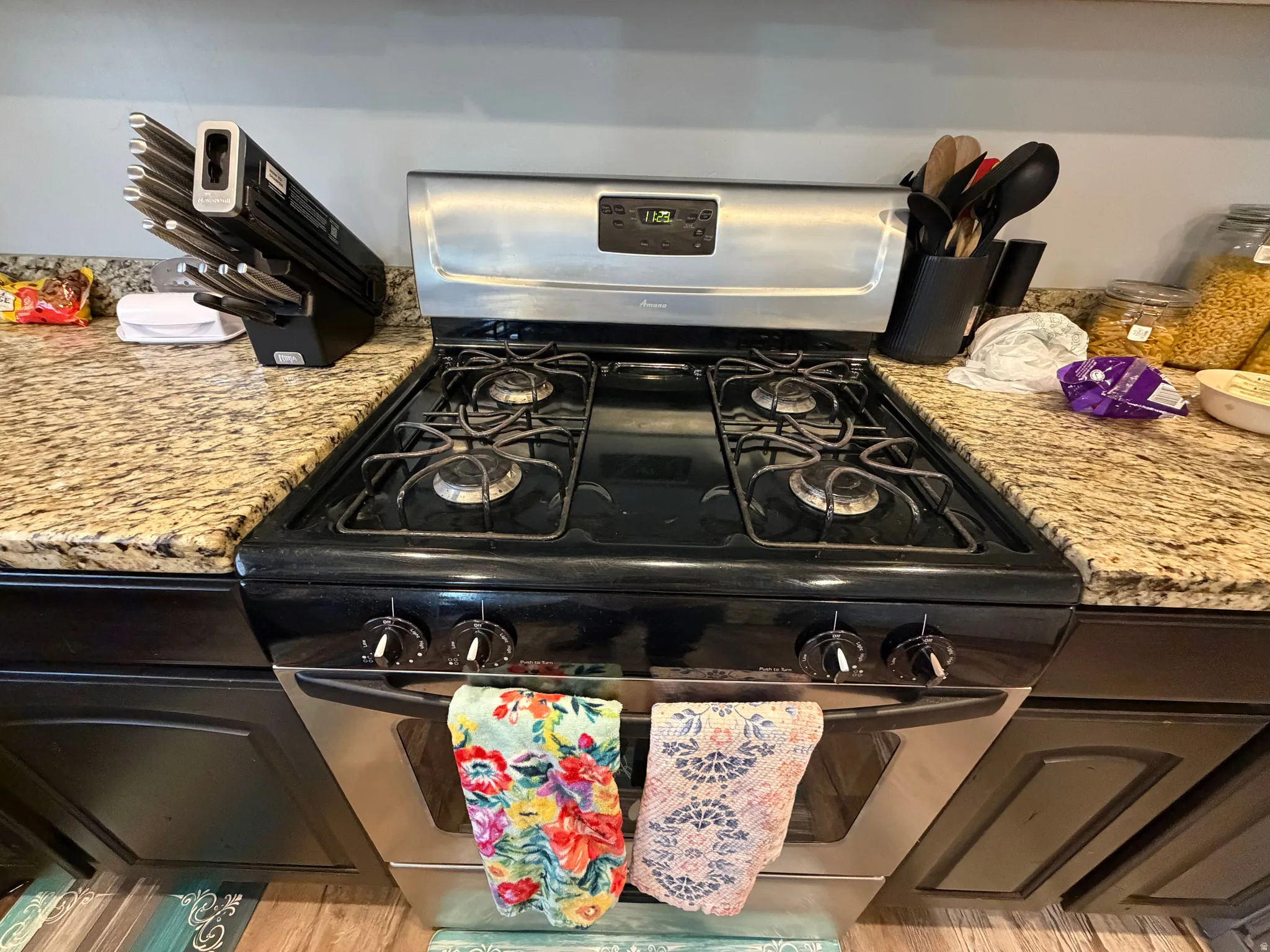 Stainless steel gas range with four burners, complemented by granite countertops and dark wood cabinetry