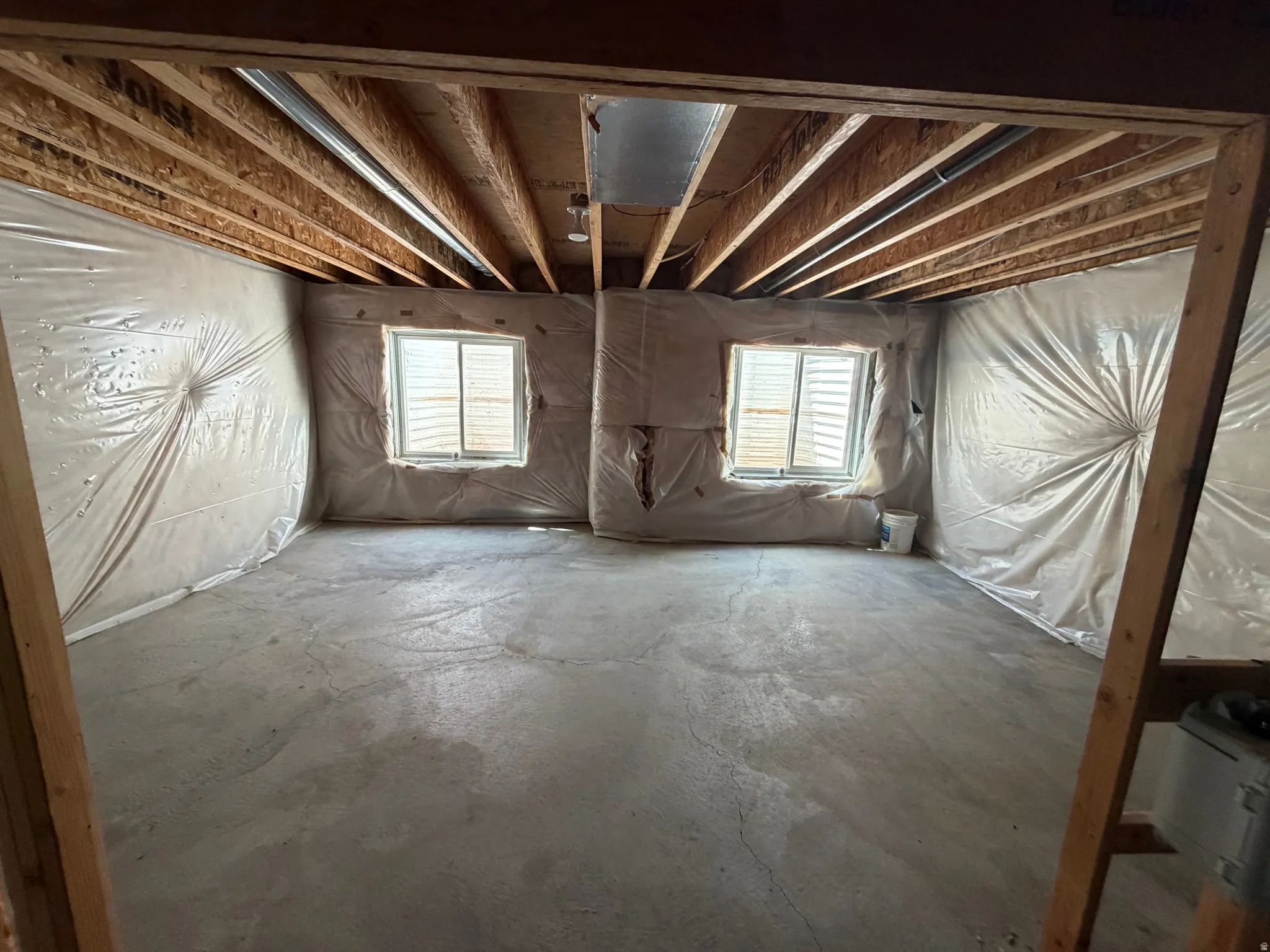 Unfinished basement with concrete flooring and visible ceiling joists
