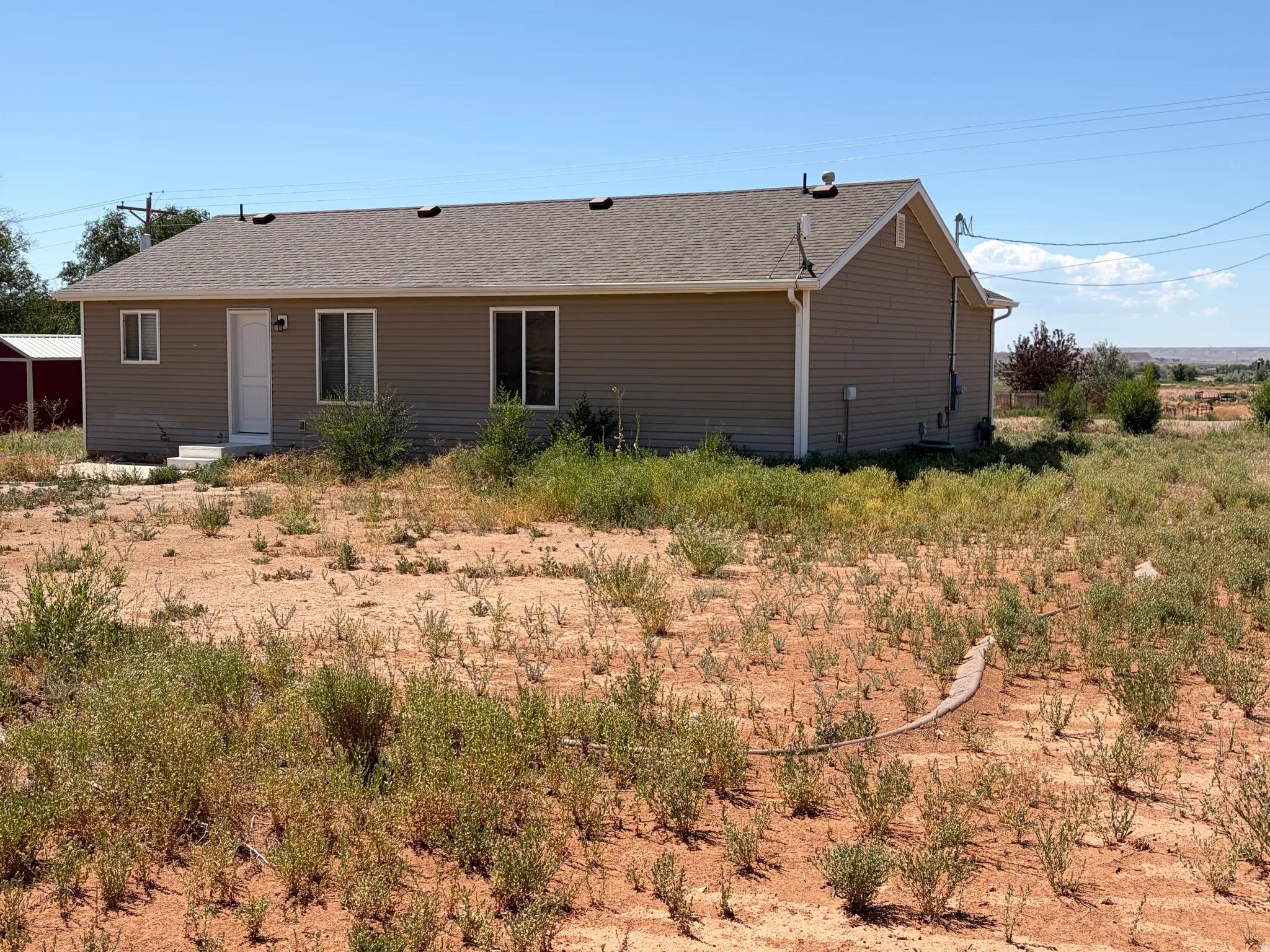 Single-story home featuring tan siding and a brown shingle roof