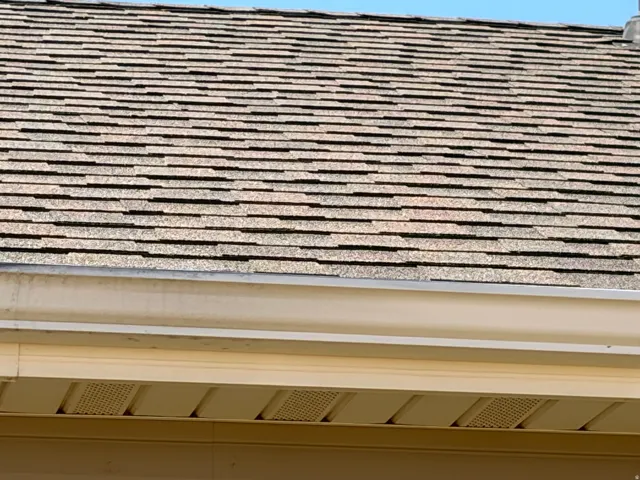 Asphalt shingle roof with light-colored gutters and perforated soffit panels