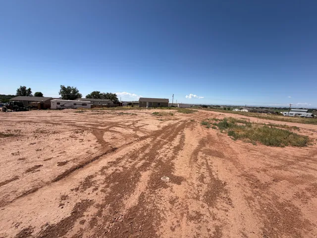 Expansive undeveloped lot featuring red earth and scattered natural vegetation