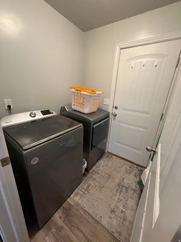 Dedicated laundry area featuring wood-finish flooring, light grey walls, and a white paneled door