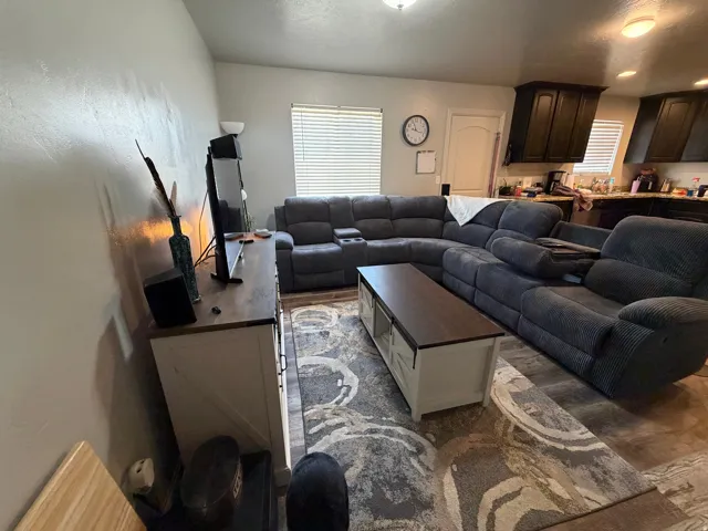 Open-concept living area featuring wood-finish flooring, a contemporary area rug, and a built-in media console with a wood-finish top