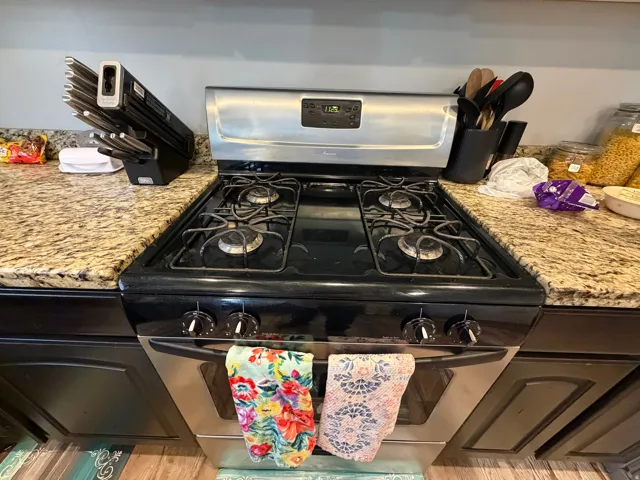 Stainless steel gas range with four burners, complemented by granite countertops and dark wood cabinetry