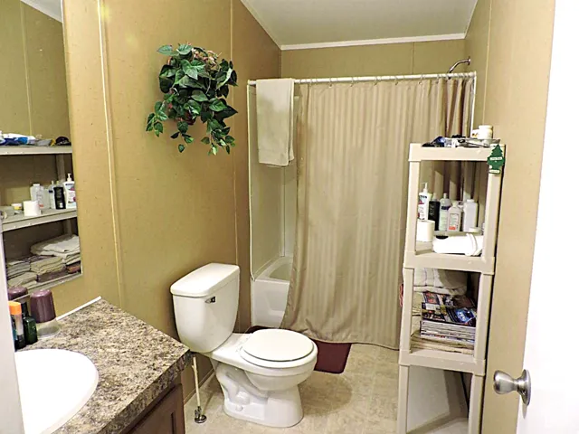 Bathroom featuring a tub/shower combination, toilet, and vanity with a laminate countertop and integrated sink