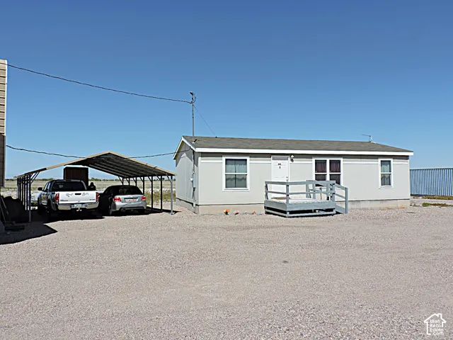 Single-story residence featuring a gravel lot, a covered carport, and a front entry deck