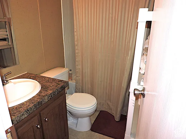 Bathroom featuring a wood-finish vanity with a built-in sink, and a toilet