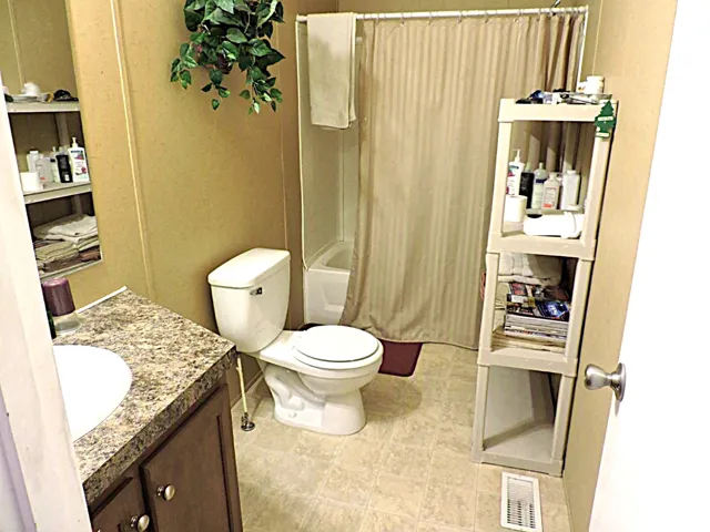 Bathroom featuring a white toilet, built-in tub with shower, and a vanity with an integrated sink and patterned countertop