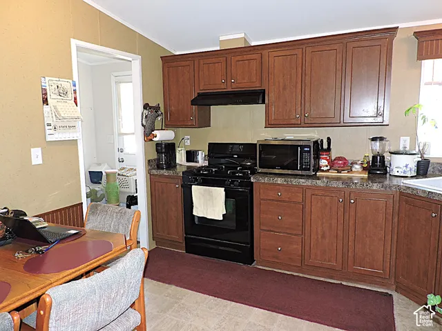 Kitchen featuring wood-finish cabinetry, dark countertops, and a full-size black propane range
